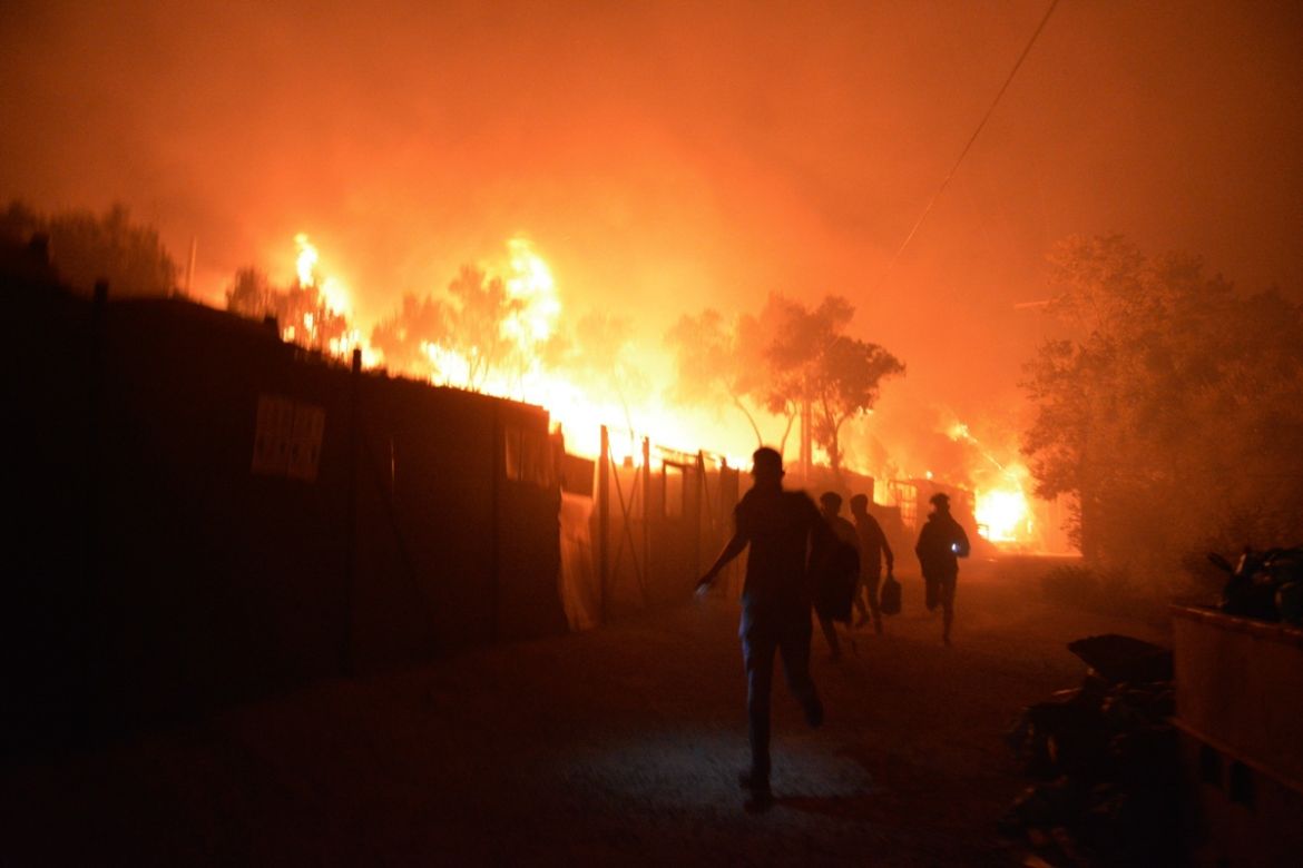 Refugees and migrants run as fire burns in the Moria refugee camp on the northeastern Aegean island of Lesbos, Greece, on Wednesday, Sept. 9, 2020. Fire Service officials say a large refugee camp on t