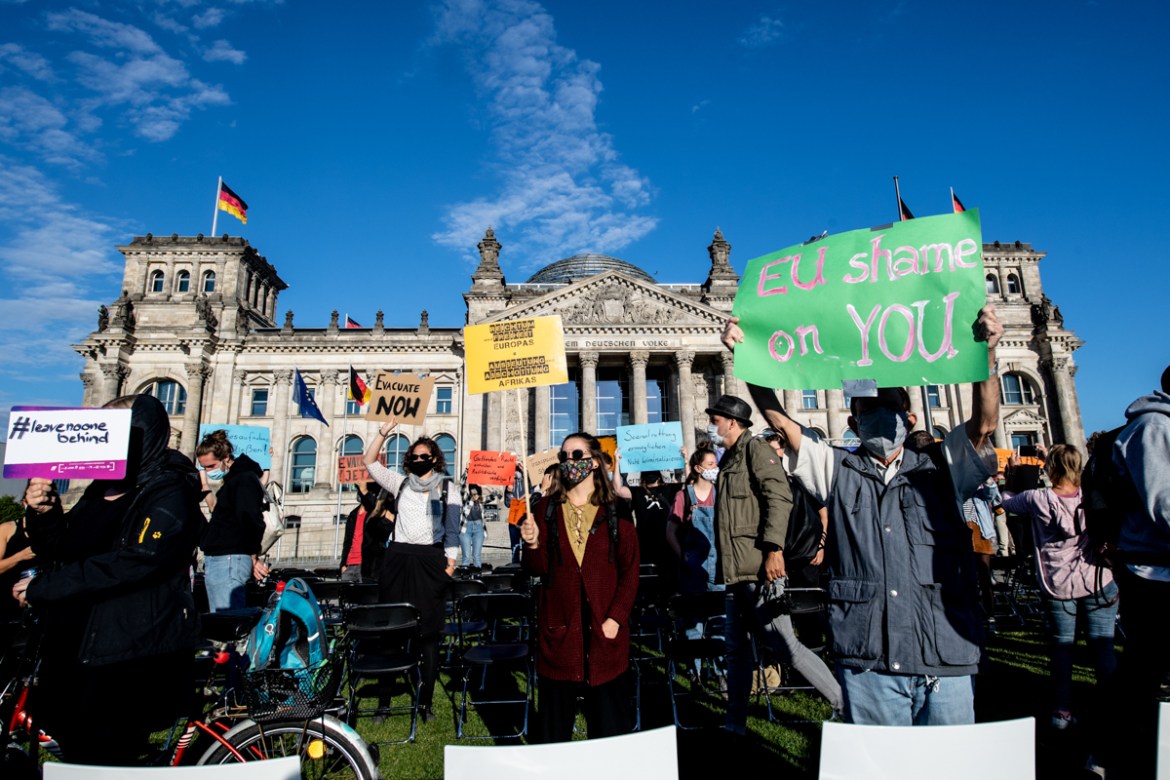 epa08652825 Protestors stand with banners in front of the symbolic 13 thousand chairs placed on the grass of the Platz der Republik in front of the German parliament Bundestag building in Berlin, Germ