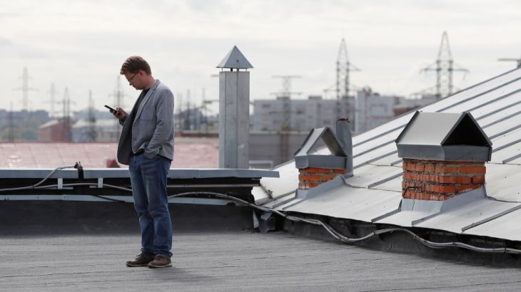 Municipal candidate and Alexei Navalny ally in Tomsk Andrei Fateev uses his mobile phone on the rooftop of an office building in Tomsk