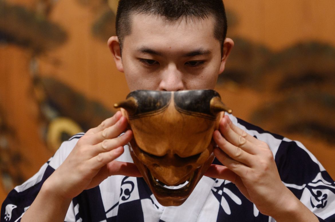 This photo taken on July 29, 2020 shows performer Kennosuke Nakamori putting on the "hannya" mask as he takes part in a rehearsal at the Kamakura Noh Theatre in the town of Kamakura in Kanagawa Prefec
