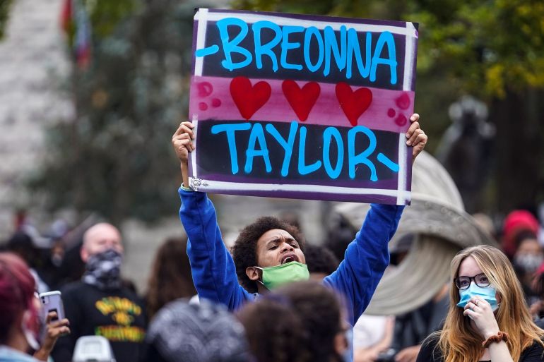 man holds up a sign that reads breonna Taylor