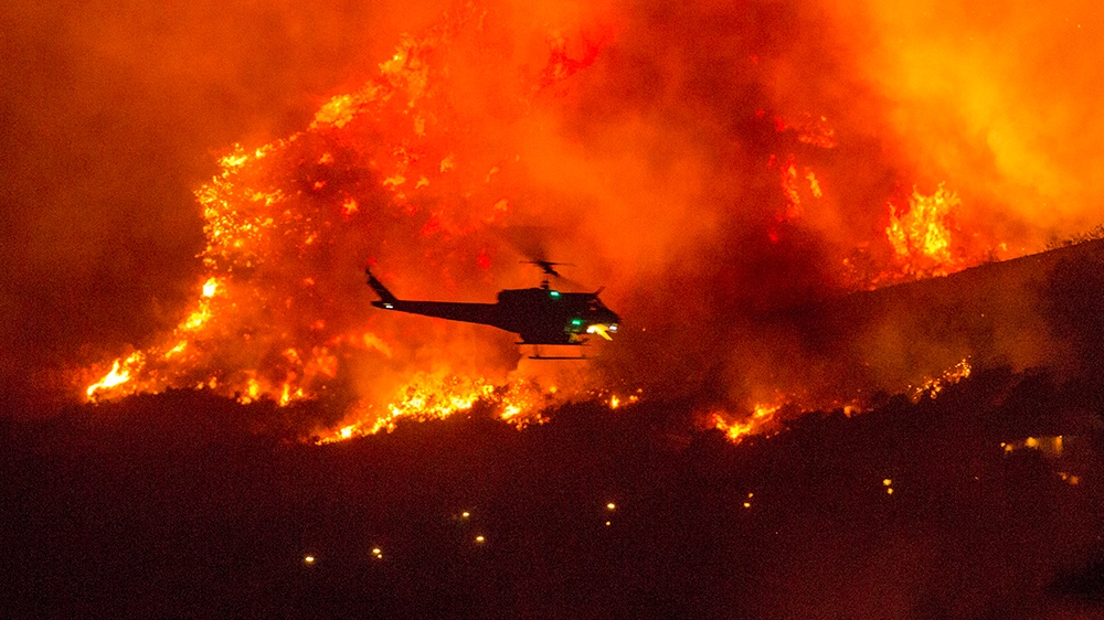 A helicopter prepares to drop water at a wildfire in Yucaipa, Calif., Saturday, Sept. 5, 2020. Three fast-spreading California wildfires sent people fleeing Saturday, with one trapping campers at a re