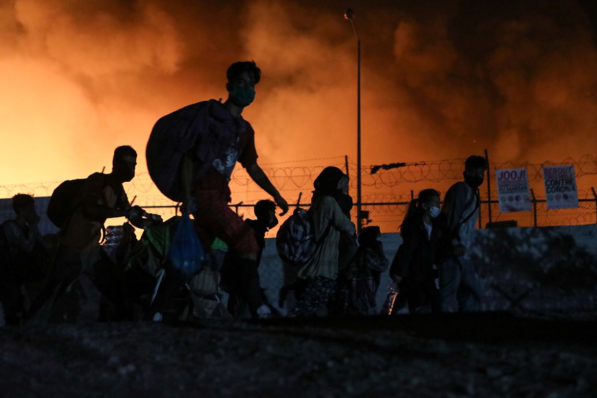 Refugees and migrants carry their belongings as they flee from a fire burning at the Moria camp, on the island of Lesbos, Greece, September 9, 2020. REUTERS/Elias Marcou