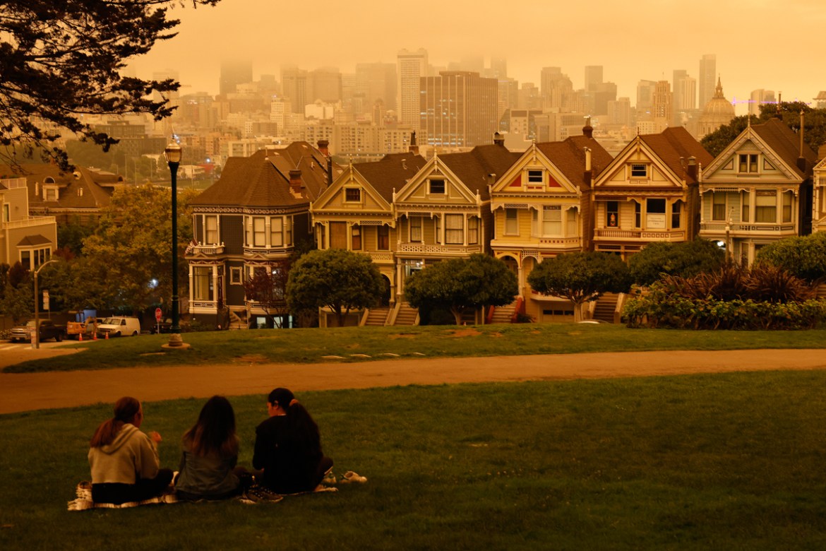 epaselect epa08657767 People sit at Alamo Square under an orange and yellow overcast sky overlooking the The Painted Ladies, the iconic row of historical Victorian homes with a downtown backdrop, in t