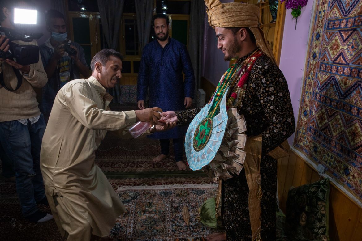 A Kashmiri man sprays sanitizer on the hand of Haseeb Mushtaq, a Kashmiri groom as he arrives at brides home during his wedding ceremony on the outskirts of Srinagar, Indian controlled Kashmir, Monday