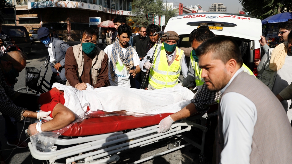 Afghan men carry an injured to a hospital after a blast in Kabul, Afghanistan