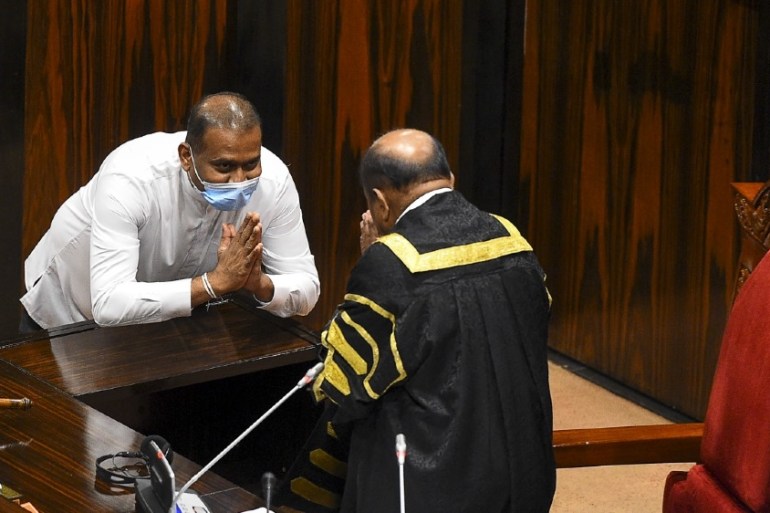 Sri Lanka''s convicted murderer Premalal Jayasekara (L) gestures after sworn in as a member of parliament from the ruling party in front of Speaker of the Parliament of Sri Lanka M