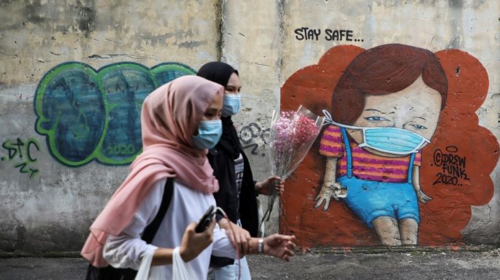 Women wearing protective masks walk past a mural, amid the coronavirus disease (COVID-19) outbreak in Kuala Lumpur