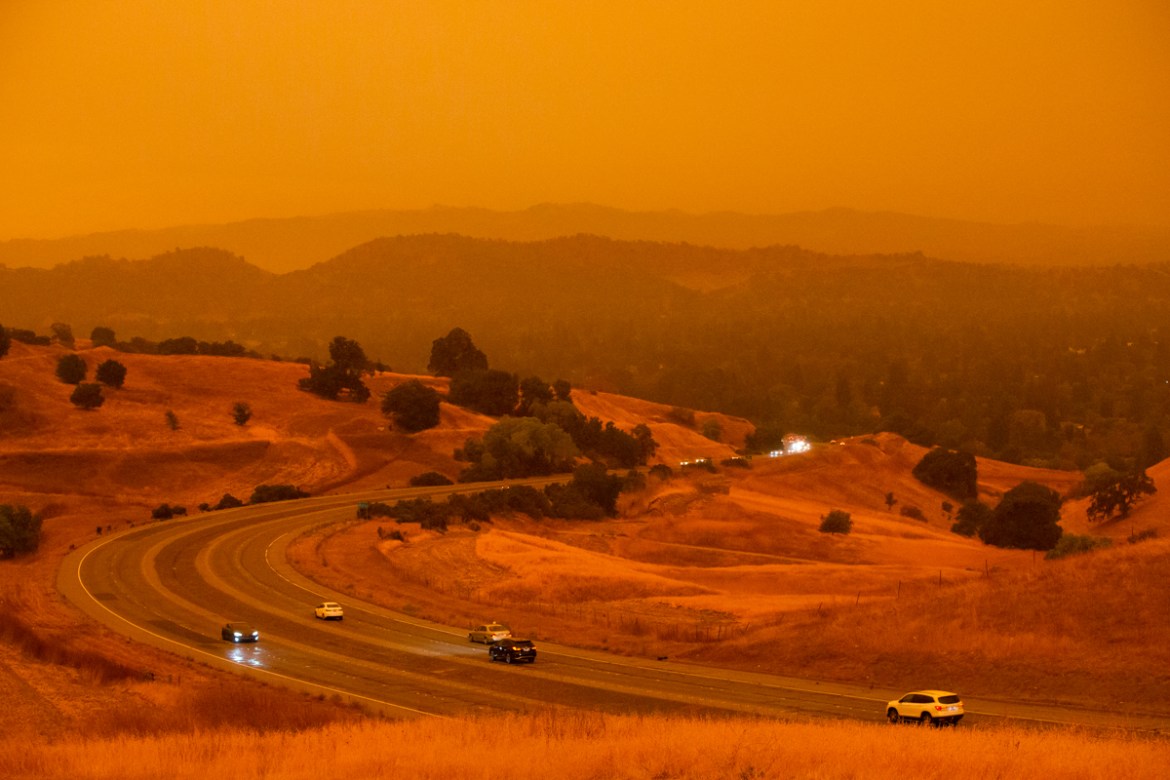 Cars drive along Ygnacio Valley Road below an orange sky filled with wildfire smoke in Concord, California on September 9, 2020, as a hazy-looking Walnut Creek can be seen in the distance through the