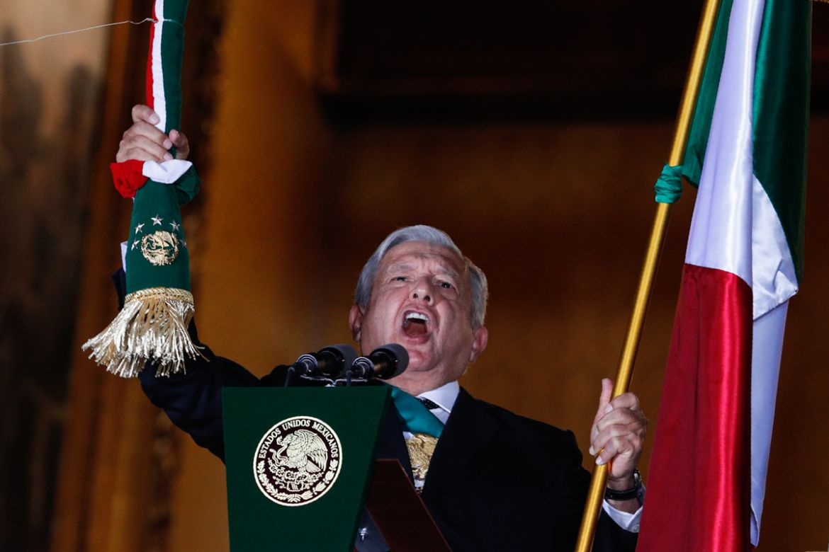 Mexican President Andres Manuel Lopez Obrador rings the bell as he gives the annual independence shout from the balcony of the National Palace to kick off subdued Independence Day celebrations amid th