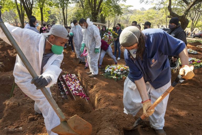 Cemetery workers bury 65-year-old Maria Joana Nascimento, whose family members, behind, suspect died of COVID-19, at Vila Formosa cemetery in Sao Paulo, Brazil, Thursday, Aug. 6, 2020. Brazil is neari