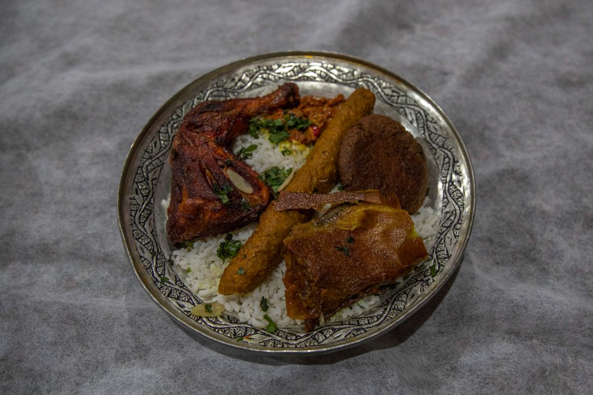 A plate full of rice dressed with wazwan dishes is kept in front of a guest during a wedding ceremony on outskirts of Srinagar, Indian controlled Kashmir, Tuesday, Sept. 15, 2020. The coronavirus pand