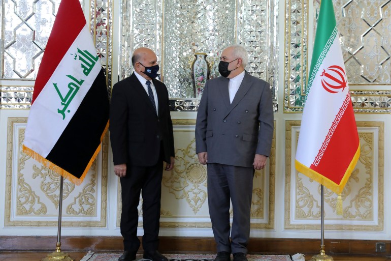 Iranian Foreign Minister Mohammad Javad Zarif, right, and his Iraqi counterpart Fuad Hussein talk while posing for media prior to their meeting in Tehran, Iran