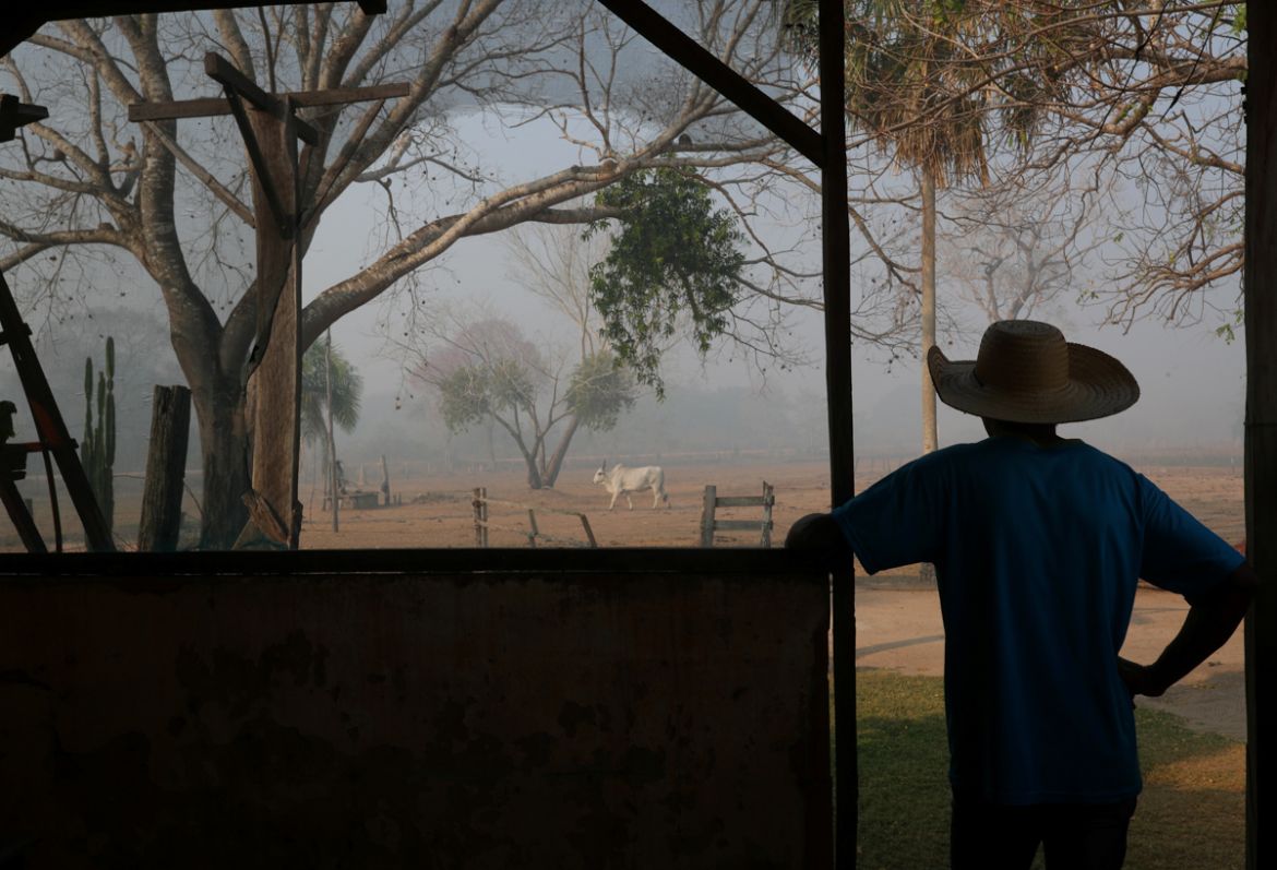 Dorvalino Conceicao Camargo, 56, stands at the ranch where he works as he looks out in front of smoke from a fire, rising into the air, in the Pantanal, the world''s largest wetland, in Pocone, Mato Gr