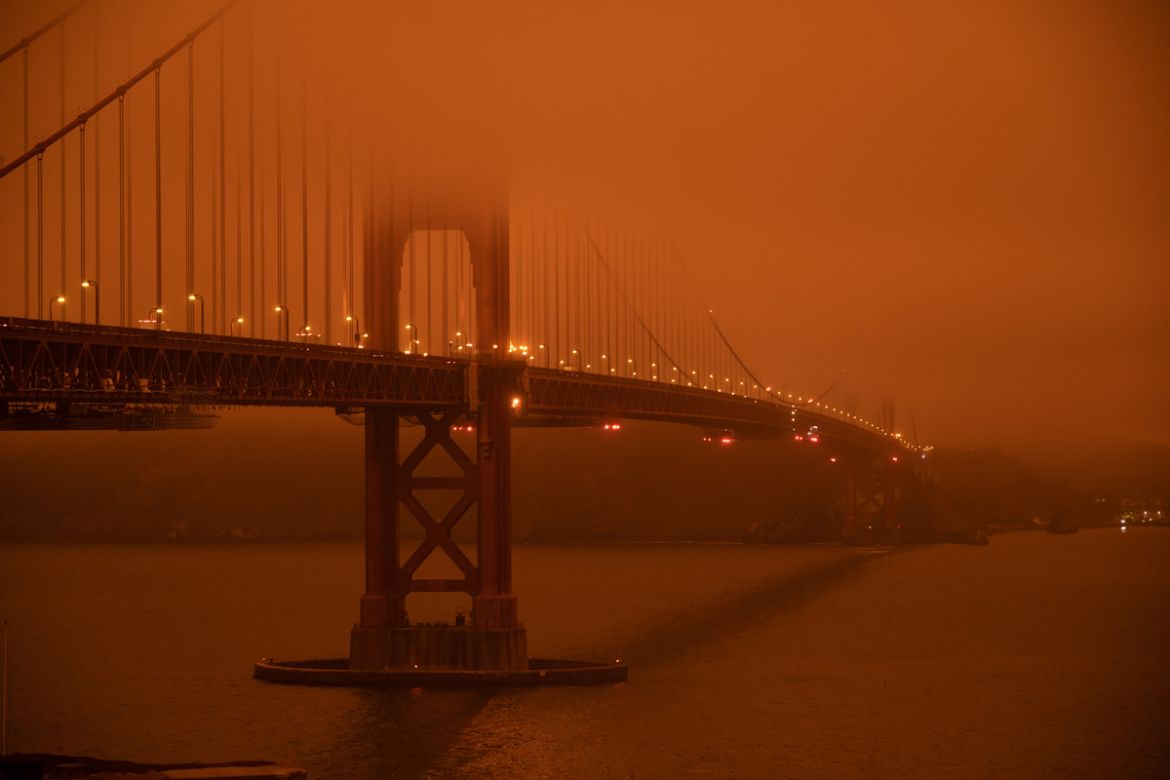 Cars drive along the Golden Gate Bridge under an orange smoke filled sky at midday in San Francisco, California on September 9, 2020. - More than 300,000 acres are burning across the northwestern stat