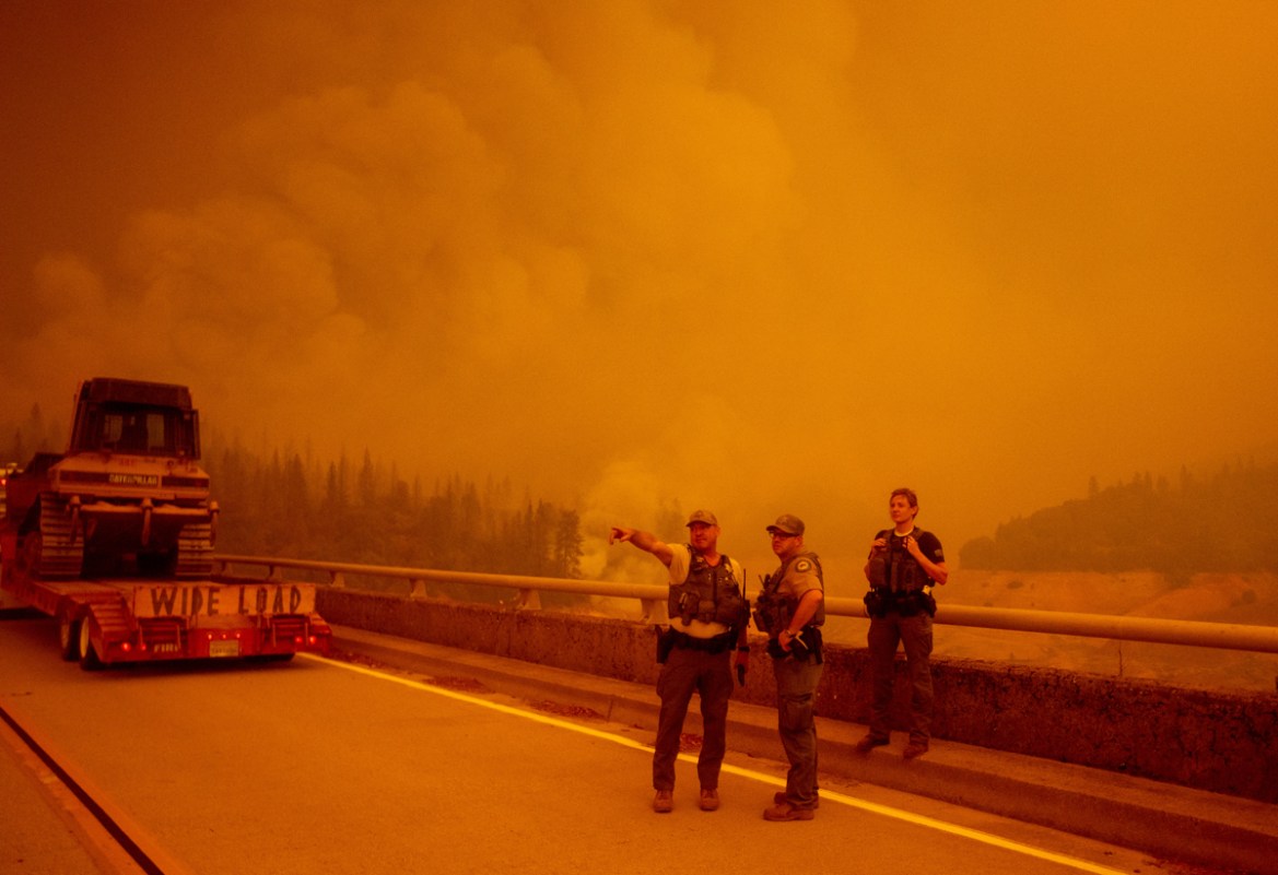 Law enforcement and fire personnel wait on the Enterprise Bridge to enter an area encroached by fire during the Bear fire, part of the North Lightning Complex fires, in unincorporated Butte County, in