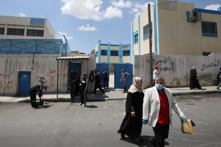 Palestinian refugees wait in front of the Amman New camp health centre (Al-Wehdat camp) to register their names to get medication amid concerns over the spread of the coronavirus disease (COVID-19), i