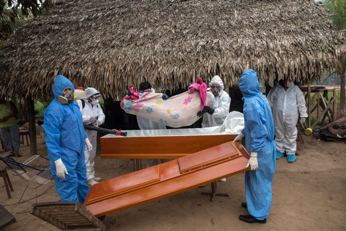 A government team removes the body of Manuela Chavez, who died from symptoms related to the new coronavirus at the age of 88, from inside her home and places her in a casket, in the Shipibo Indigenous