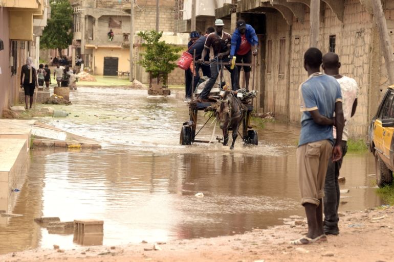 Residents transport their belongings with a horse pulling a cart through flood waters in the Keurs Massar area in Dakar on September 7, 2020 after heavy rains in Senegal. The Senegalese government cam