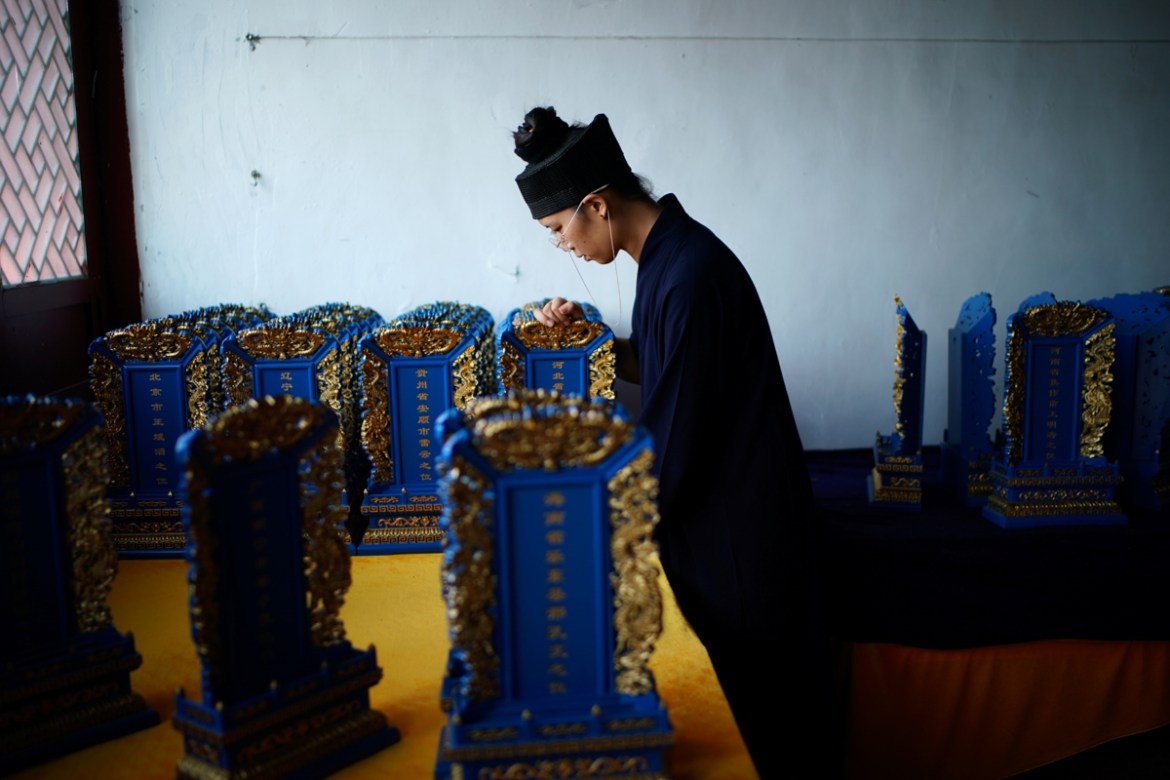 Priest Zhang Zongyan, 27, a politics study graduate, arranges memorial tablets at Taoist temple Jiuyang Palace, in Laiwu of Jinan city, Shandong province, China, September 7, 2020. During her studies