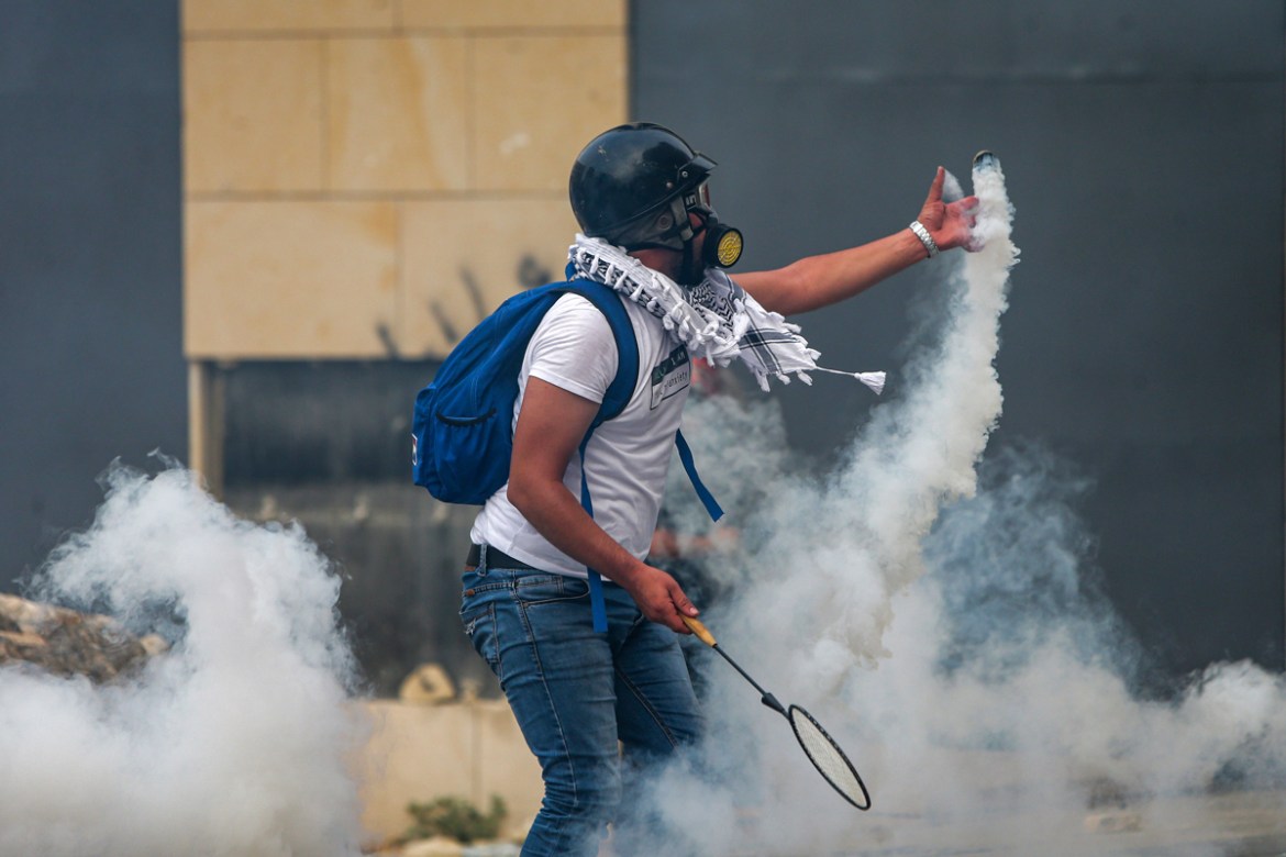 A protester uses a badminton racket to serve back a tear gas canister during clashes with security forces amidst an anti-government demonstration in the centre of Lebanon''s capital Beirut during on Se