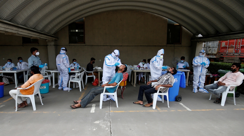 Healthcare workers wearing personal protective equipment (PPE) take swabs from flour mill workers, amidst the coronavirus disease (COVID-19) outbreak, in Moriya village on the outskirts of Ahmedabad, 