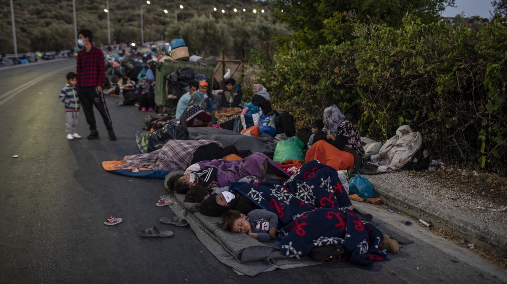 Migrants sleep on the road near the Moria refugee camp on the northeastern island of Lesbos, Greece, Thursday, Sept. 10, 2020. A second fire in Greece's notoriously overcrowded Moria refugee camp dest