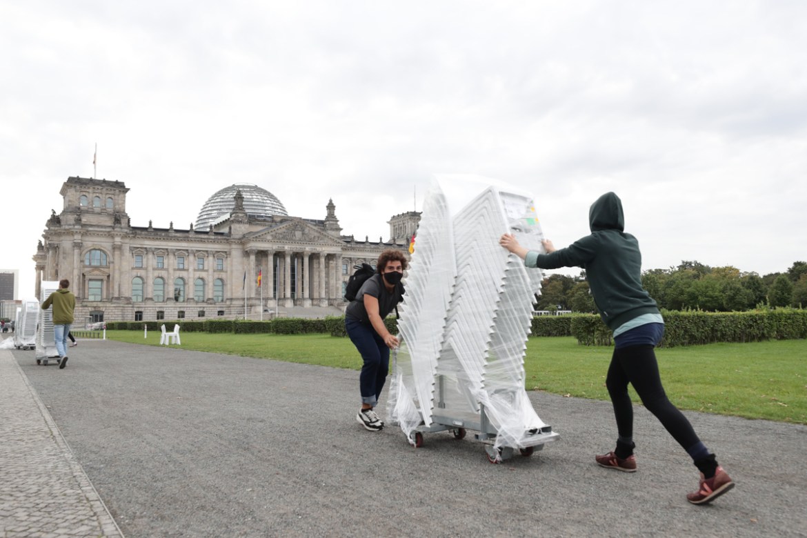 epa08651934 Activists from Seebruecke and Sea-Watch put chairs on the grass of the Platz der Republick in front of the German parliament Bundestag building in Berlin, Germany, 07 September 2020. As a