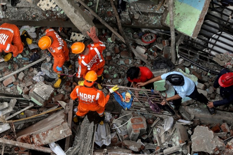 National Disaster Response Force (NDRF) officials and firemen remove debris as they look for survivors after a three-storey residential building collapsed in Bhiwandi on the outskirts of Mumbai, India
