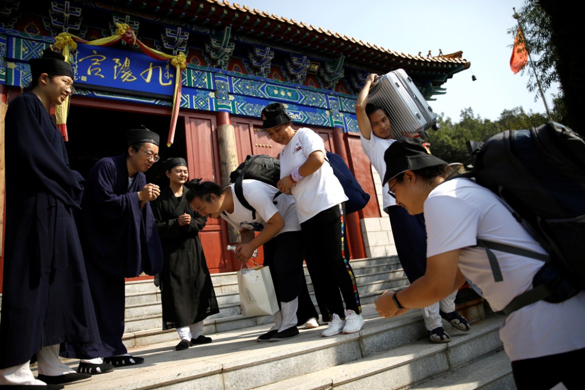 Priest Chen Hongyu (R) and priest Shang Shishen, 27, (L4) bow to priest Liang Xingyang as they leave the temple for returning a Taoist college for the new semester, at the entrance of Taoist temple