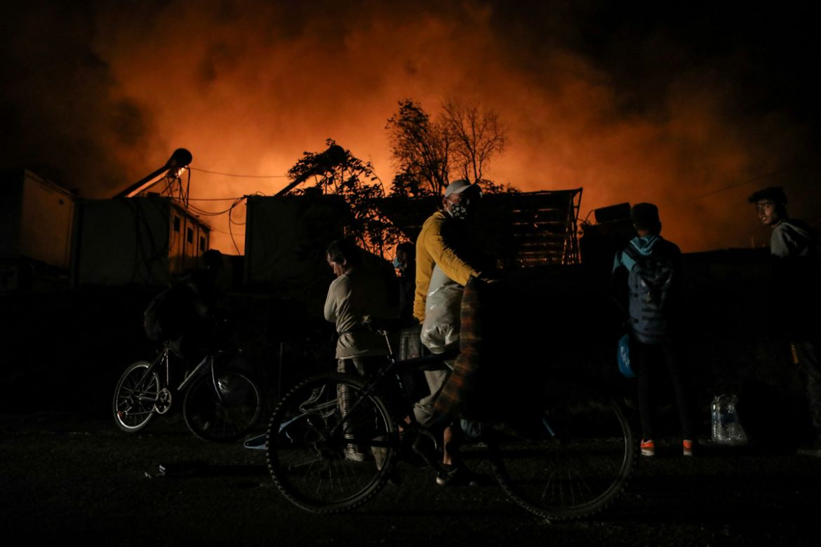Refugees and migrants carry their belongings as they flee from a fire burning at the Moria camp on the island of Lesbos, Greece, September 9, 2020. REUTERS/Elias Marcou TPX IMAGES OF THE DAY