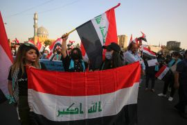 Iraqis carry national flags as they demonstrate in the capital Baghdad's Al-Firdous Square on October 1, 2020, during the commemoration of the first anniversary of the massive decentralised anti-government protest movement against unemployment, poor public services, and endemic corruption. Thousands of Iraqis gathered today in the capital Baghdad and in the country's south on the first anniversary of the start of unprecedented protests demanding the fall of the ruling class. AHMAD AL-RUBAYE / AFP