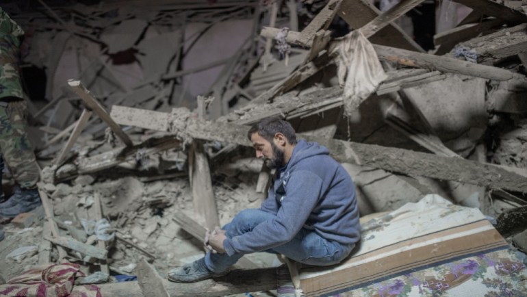 Man sits among rubble in Ganja after alleged Armenian attack