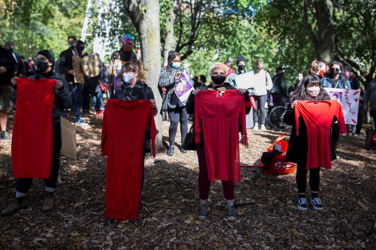 Women hold up red dresses during a protest