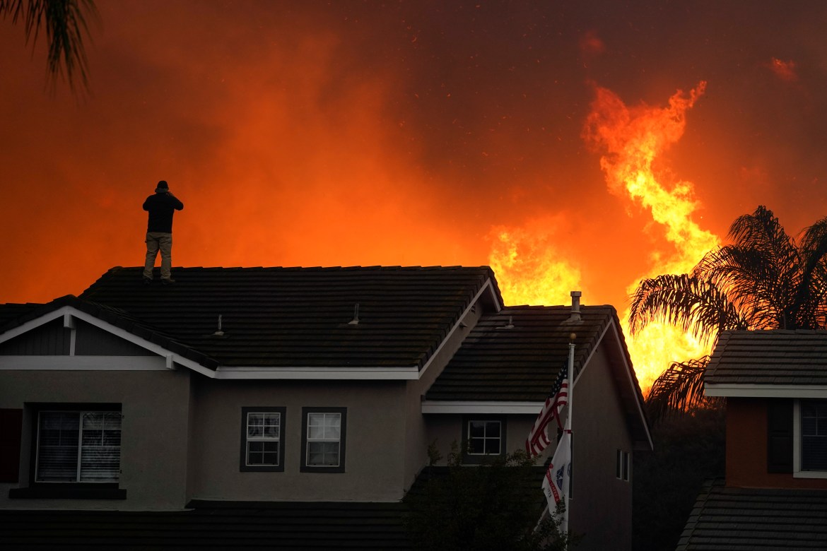 Herman Termeer, 54, está no telhado de sua casa enquanto um incêndio queima em Chino Hills.  [Foto de Jae C. Hong / AP]