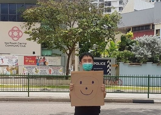 Jolovan Wham is being charged for an offence under the Public Order Act for holding a placard with a smiley face outside a police station on March 28 [Jolovan Wham/Handout via Reuters]