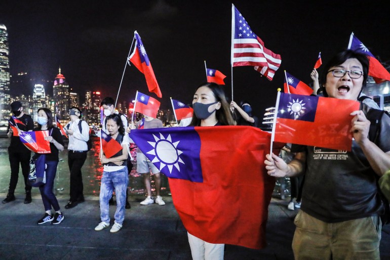 People hold Taiwanese flags as they join others at a rally to mark Taiwan's National Day, in the Tsim Sha Tsui district in Hong Kong [File: Kin Cheung/AP Photo]