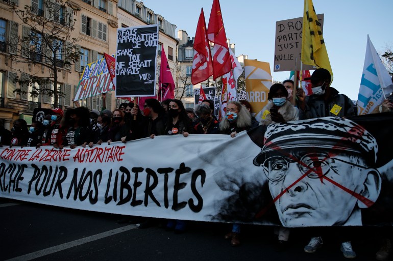 Protesters hold a banner reading 'For our freedom' and show a defaced portrait of Paris police prefect Didier Lallement during a demonstration in Paris against the security law [Francois Mori/AP]