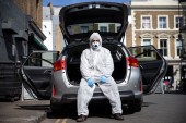 Uber driver Yasar Gorur wears personal protective equipment while cleaning his vehicle on April 14, 2020 in London, United Kingdom. Gorur says he wipes down the seats in his car every 2-3 trips and wears personal protective equipment whenever he drives [Hollie Adams/Getty Images]