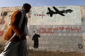 A man walks past a graffiti, denouncing strikes by US drones in Yemen, painted on a wall in Sanaa November 13, 2014 [Khaled Abdullah/Reuters]