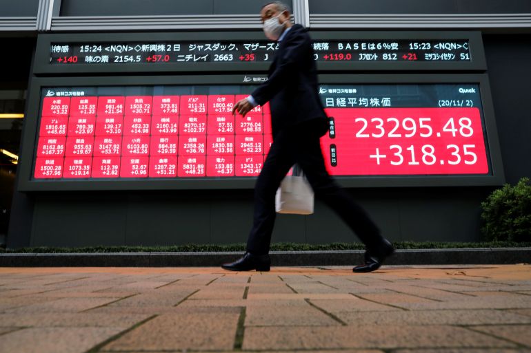 A man walks past stock figures in Tokyo, Japan.