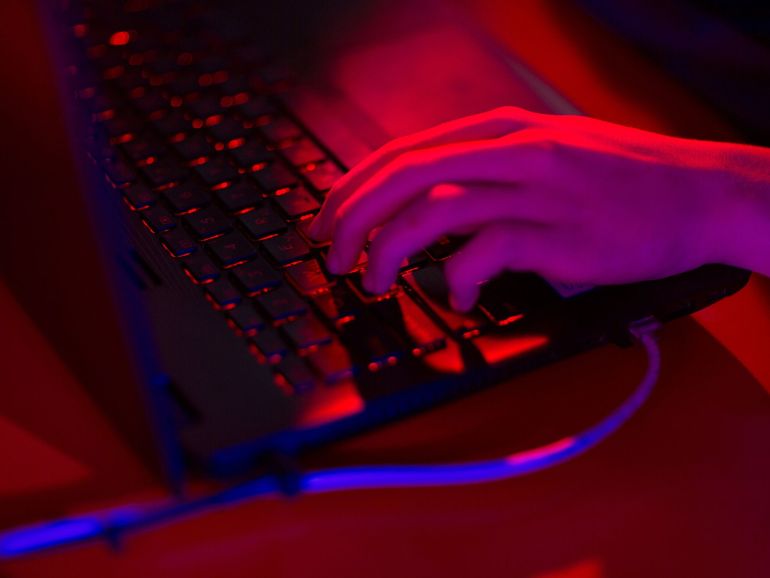 Red light illuminates the keys of a laptop