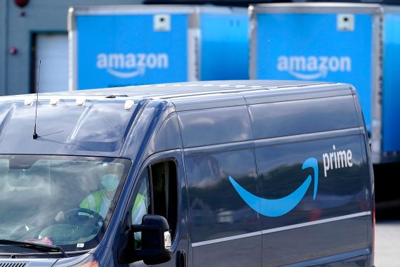 an Amazon Prime logo appears on the side of a delivery van as it departs an Amazon Warehouse location in Dedham, Mass., US