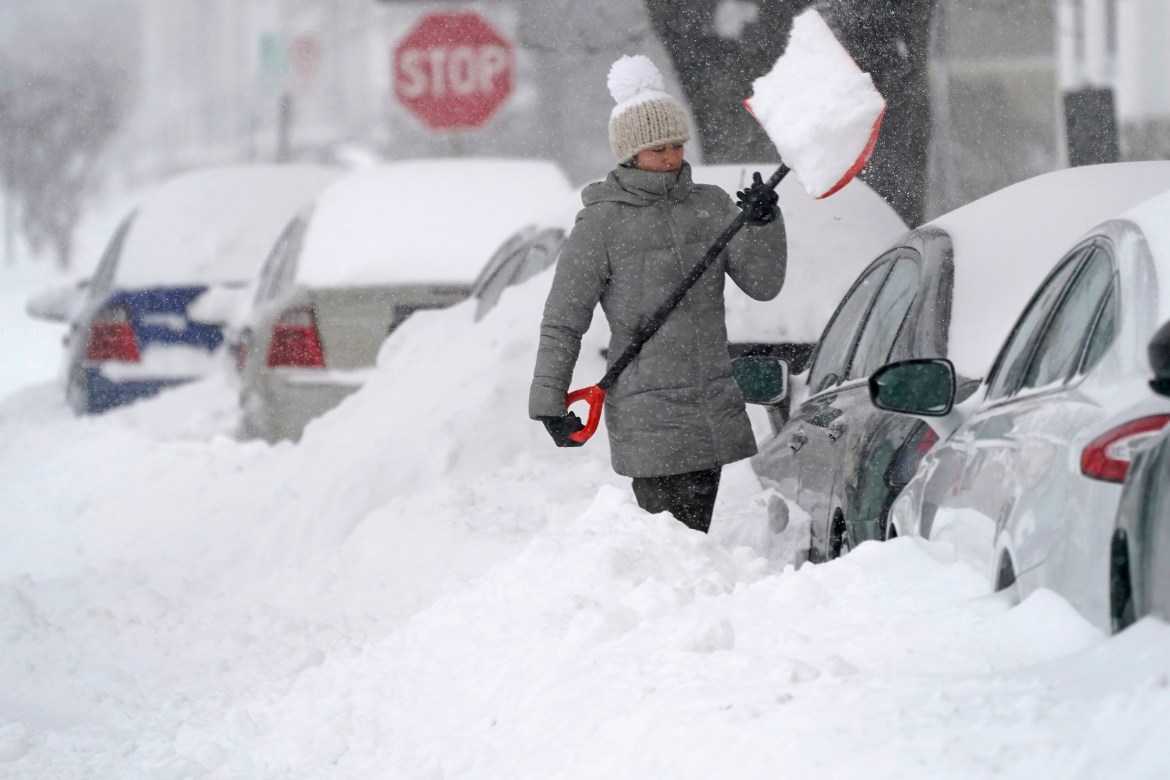 A woman tosses a shovel full of snow while digging out her car, Thursday morning, in Manchester, New Hampshire. [Charles Krupa/AP Photo]