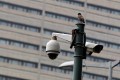A bird sits atop a closed-circuit television (CCTV) camera pole at a traffic intersection