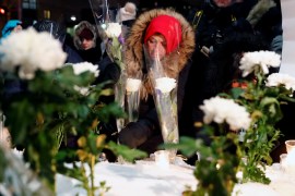 A woman leaves a flower during the one-year anniversary vigil for the Quebec City mosque victims