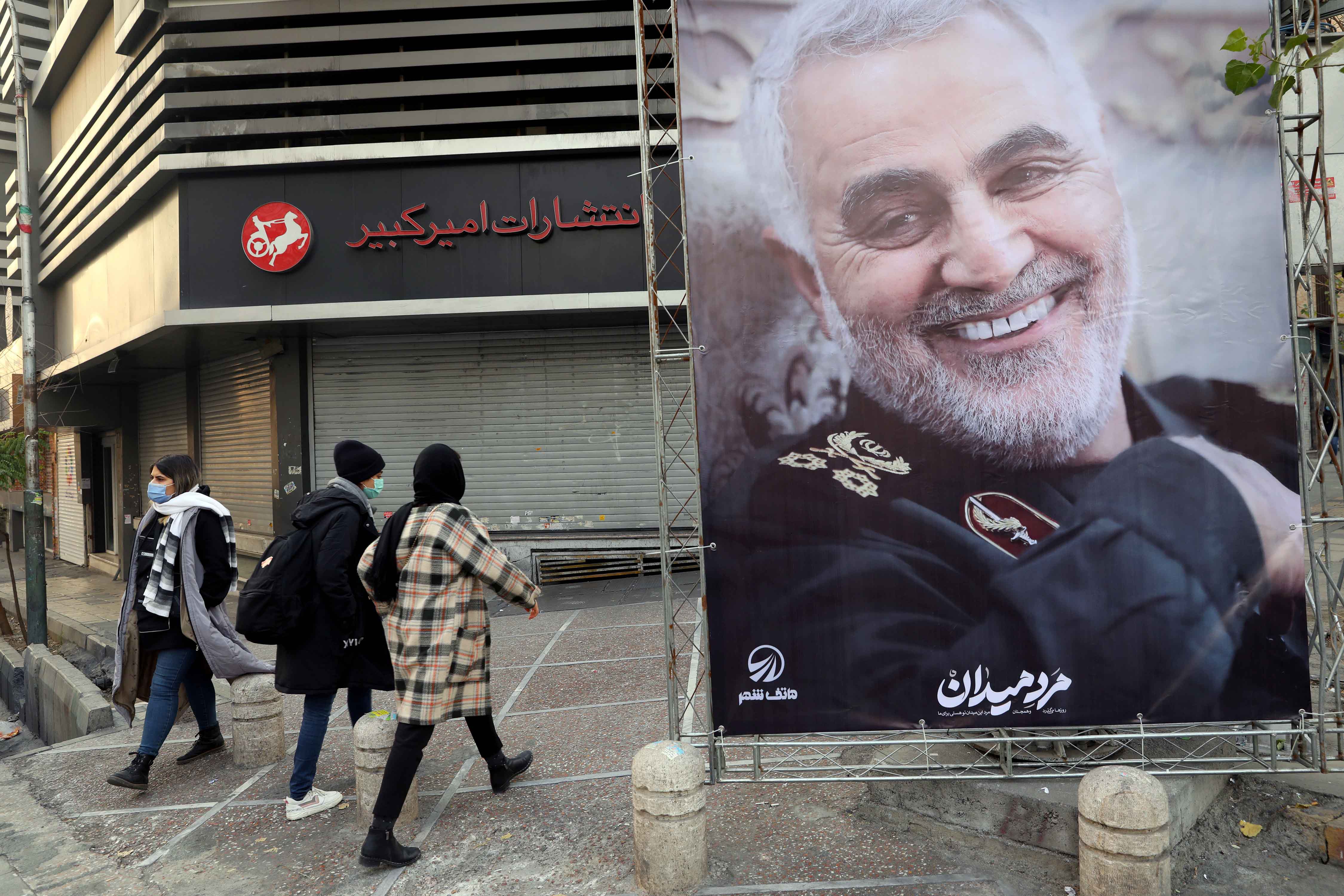 La gente a Teheran cammina vicino a un poster del generale Qassem Soleimani,