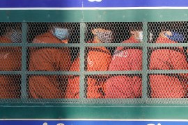 Dressed in orange prison uniforms and seated shoulder to shoulder in an open but barred, prison van, dozens of former opposition activists are brought to court