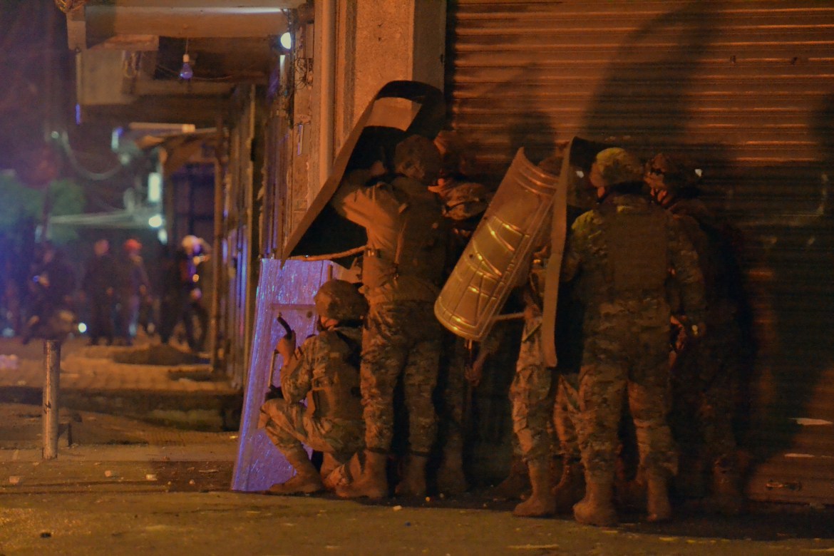 Lebanese soldiers covering themselves as anti-lockdown protesters throw stones in Tripoli. [EPA]