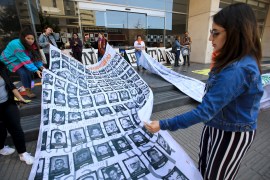 Protesters hold up a banner with images of people killed in 'false positives' in Colombia